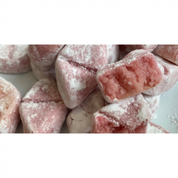 zdjęcie przedstawiające kawałki czerwonego marcepanu w otoczce z cukru pudru